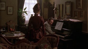 Movie still from “Topsy-Turvy” (1999), directed by Mike Leigh – A man and a woman playing a piano in a living room; Medium shot, Over the shoulder angle