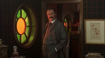 Movie still from “Topsy-Turvy” (1999), directed by Mike Leigh – A man standing in front of a stained glass window; Medium shot, Low angle