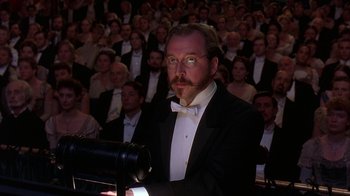 Movie still from “Topsy-Turvy” (1999), directed by Mike Leigh – A man in a suit and tie in front of an audience; Medium shot, Low angle