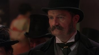 Movie still from “Topsy-Turvy” (1999), directed by Mike Leigh – A person wearing a suit and a hat; Close Up shot, Low angle