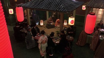 Movie still from “Topsy-Turvy” (1999), directed by Mike Leigh – A group of people sitting at a table in front of a gazebo; Wide shot, High angle
