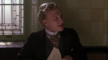 Movie still from “Topsy-Turvy” (1999), directed by Mike Leigh – A man wearing a suit and tie sitting in a room; Close Up shot, Low angle