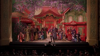 Movie still from “Topsy-Turvy” (1999), directed by Mike Leigh – A scene of a stage show with a crowd of people watching it; Extreme Wide shot, High angle