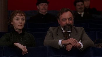 Movie still from “Topsy-Turvy” (1999), directed by Mike Leigh – A man and a woman sitting in a movie theater; Medium shot, Low angle
