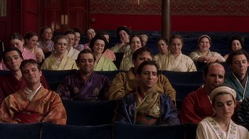 Movie still from “Topsy-Turvy” (1999), directed by Mike Leigh – A group of people sitting in seats in a theater; Medium shot, High angle