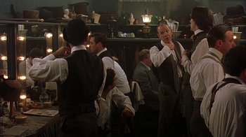 Movie still from “Topsy-Turvy” (1999), directed by Mike Leigh – A group of men standing around in a room; Medium shot, Over the shoulder angle