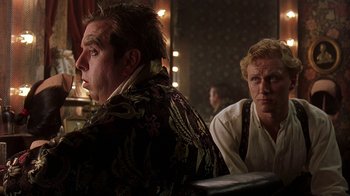 Movie still from “Topsy-Turvy” (1999), directed by Mike Leigh – Two men are sitting in front of each other; Medium shot, Over the shoulder angle