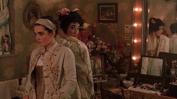 Movie still from “Topsy-Turvy” (1999), directed by Mike Leigh – A couple of women standing next to each other in front of a mirror; Medium shot, Over the shoulder angle