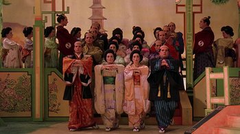 Movie still from “Topsy-Turvy” (1999), directed by Mike Leigh – A group of people dressed in traditional japanese clothing; Wide shot, High angle