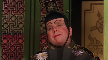 Movie still from “Topsy-Turvy” (1999), directed by Mike Leigh – A man with a black hat is wearing a black and gold outfit; Close Up shot, Over the shoulder angle