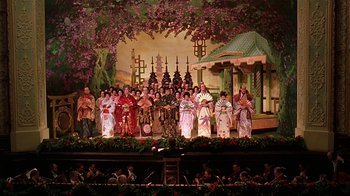Movie still from “Topsy-Turvy” (1999), directed by Mike Leigh – A group of people in traditional japanese garb on stage; Extreme Wide shot, High angle
