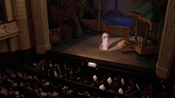 Movie still from “Topsy-Turvy” (1999), directed by Mike Leigh – An audience is watching a performance in a theater; Extreme Wide shot, High angle