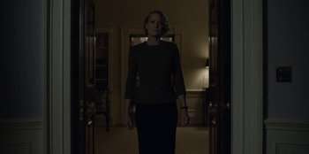 Movie still from “House of Cards” (2013), created by Beau Willimon – A woman standing in a dark room in front of a door; Medium shot, Low angle