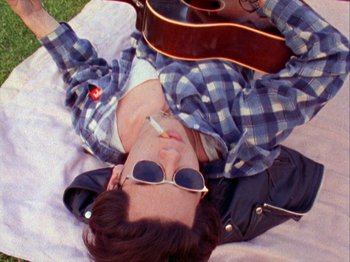 A man laying on the ground holding a guitar