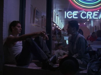 Two men sitting on a bench in front of an ice cream sign