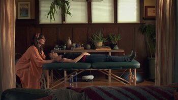 Movie still from “Touchy Feely” (2013), directed by Lynn Shelton – A woman laying on a massage table in a living room; Wide shot, Over the shoulder angle
