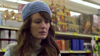 Movie still from “Touchy Feely” (2013), directed by Lynn Shelton – A person wearing a hat in a store; Close Up shot, Over the shoulder angle