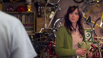Movie still from “Touchy Feely” (2013), directed by Lynn Shelton – A woman standing in front of a bicycle in a room; Medium shot, Over the shoulder angle
