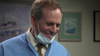Movie still from “Touchy Feely” (2013), directed by Lynn Shelton – A man wearing a surgical face mask smiles; Close Up shot, Over the shoulder angle