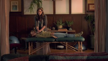 Movie still from “Touchy Feely” (2013), directed by Lynn Shelton – A woman is standing over a woman lying on a massage table; Medium shot, Over the shoulder angle