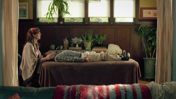 Movie still from “Touchy Feely” (2013), directed by Lynn Shelton – A person laying on a bed in a living room; Wide shot, High angle