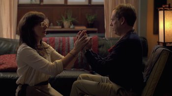 Movie still from “Touchy Feely” (2013), directed by Lynn Shelton – A man and a woman sitting on a couch holding hands; Medium shot, Over the shoulder angle