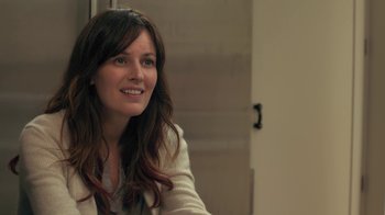 Movie still from “Touchy Feely” (2013), directed by Lynn Shelton – A woman sitting in a room smiling for the camera; Close Up shot, Over the shoulder angle