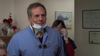 Movie still from “Touchy Feely” (2013), directed by Lynn Shelton – A man in a blue lab coat and a woman wearing glasses; Close Up shot, Over the shoulder angle