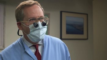 Movie still from “Touchy Feely” (2013), directed by Lynn Shelton – A man wearing a surgical mask while wearing glasses; Close Up shot, Over the shoulder angle