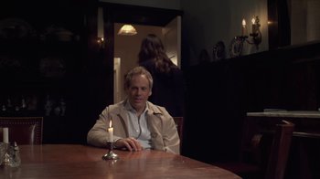 Movie still from “Touchy Feely” (2013), directed by Lynn Shelton – A man sitting at a wooden table with a candle; Medium shot, Over the shoulder angle
