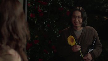 Movie still from “Touchy Feely” (2013), directed by Lynn Shelton – A woman holding a yellow flower in front of a bush; Medium shot, Over the shoulder angle