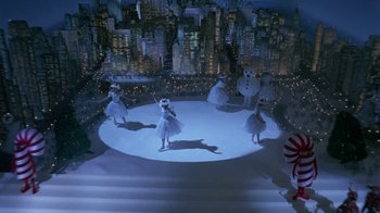 Movie still from “Toys” (1992), directed by Barry Levinson – A group of people standing on top of an ice rink in front of a city skyline; Extreme Wide shot, High angle