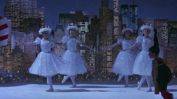 Movie still from “Toys” (1992), directed by Barry Levinson – A group of young ballerinas performing in front of a city skyline at night; Wide shot, High angle