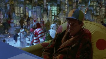 Movie still from “Toys” (1992), directed by Barry Levinson – An older man wearing a hat sitting on a chair; Medium shot, High angle
