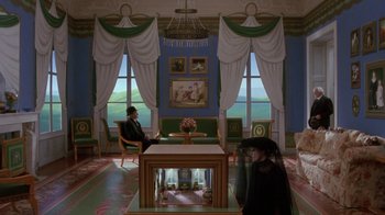 Movie still from “Toys” (1992), directed by Barry Levinson – Two people are sitting at a table in a living room; Wide shot, High angle