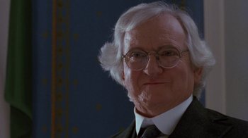 Movie still from “Toys” (1992), directed by Barry Levinson – An older man wearing glasses and a suit; Close Up shot, Over the shoulder angle