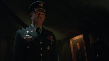 Movie still from “Toys” (1992), directed by Barry Levinson – A man in a military uniform standing in front of a painting; Medium shot, Low angle