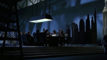 Movie still from “Toys” (1992), directed by Barry Levinson – A group of people sitting at a table in front of a city skyline; Extreme Wide shot, Low angle