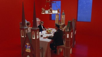 Movie still from “Toys” (1992), directed by Barry Levinson – A group of people sitting around a table; Extreme Wide shot, High angle