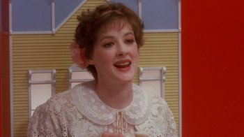 Movie still from “Toys” (1992), directed by Barry Levinson – A woman in a white dress is smiling; Close Up shot, Over the shoulder angle