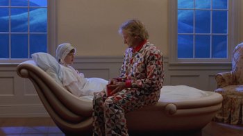 Movie still from “Toys” (1992), directed by Barry Levinson – A woman sitting next to a bed with a child; Wide shot, High angle