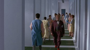 Movie still from “Toys” (1992), directed by Barry Levinson – A group of people walking down a long hallway; Wide shot, High angle