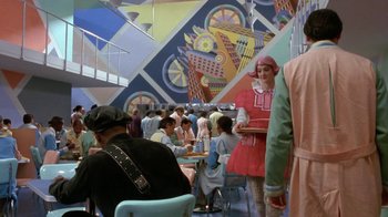 Movie still from “Toys” (1992), directed by Barry Levinson – A group of people sitting at tables in a restaurant; Wide shot, Over the shoulder angle