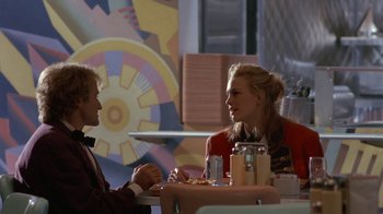Movie still from “Toys” (1992), directed by Barry Levinson – A man and a woman are sitting at a table; Medium shot, Over the shoulder angle