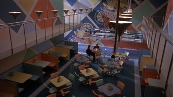 Movie still from “Toys” (1992), directed by Barry Levinson – Two people sitting at a table in a restaurant; Extreme Wide shot, High angle