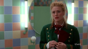 Movie still from “Toys” (1992), directed by Barry Levinson – A woman in a green jacket and a red tie in front of a bathroom mirror; Close Up shot, Over the shoulder angle