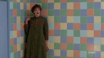 Movie still from “Toys” (1992), directed by Barry Levinson – A woman standing in front of a tiled wall; Medium shot, Overhead angle