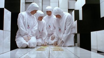 Movie still from “Toys” (1992), directed by Barry Levinson – A group of people in white robes and white hats; Wide shot, Overhead angle