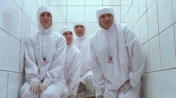 Movie still from “Toys” (1992), directed by Barry Levinson – A group of people dressed in white sitting in a room; Medium shot, Low angle