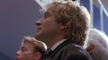 Movie still from “Toys” (1992), directed by Barry Levinson – A person wearing a suit and tie; Close Up shot, Low angle